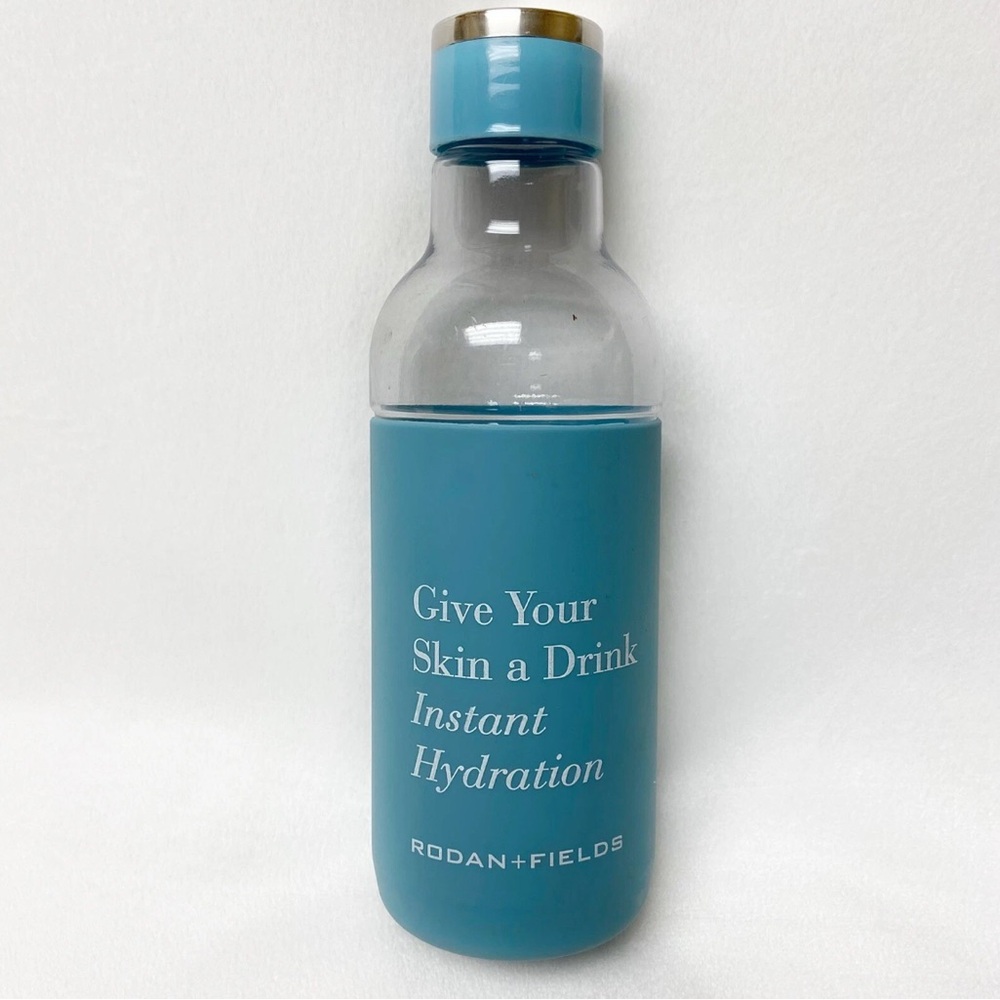 RODAN & FIELDS CLEAR PLASTIC WATER BOTTLE WITH BLUE RUBBER SLEEVE PROTECTOR